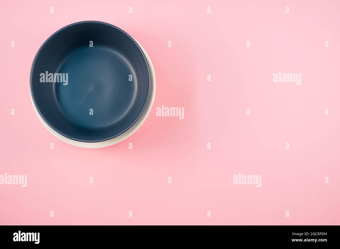 Top view of empty ceramic black and white plates on a pink background ...