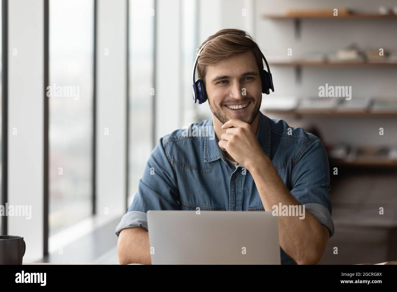 Happy student guy in headphones using laptop for distance studying Stock Photo