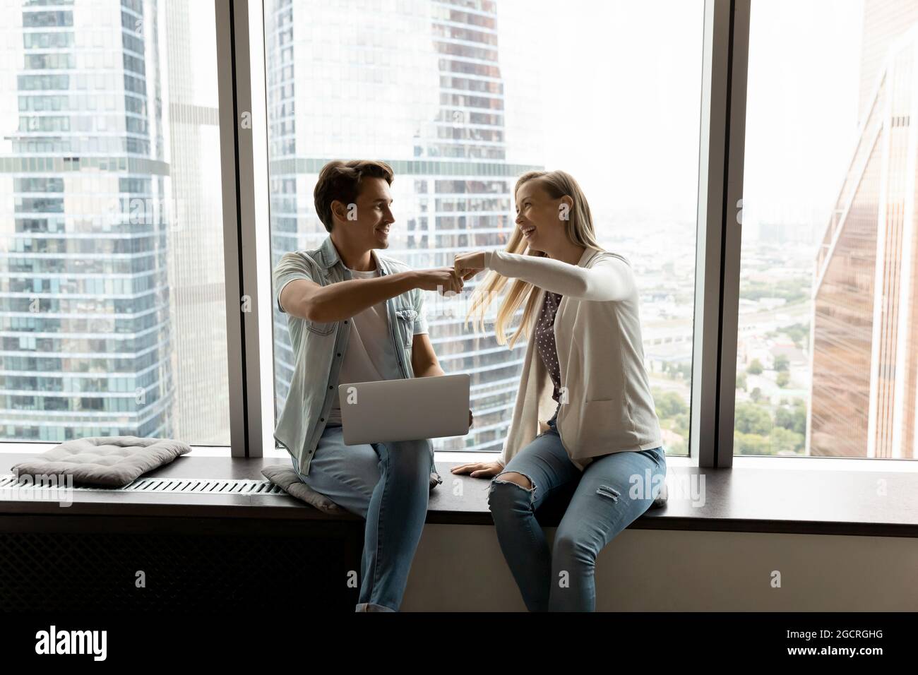 Happy business teammates, office friends, buddies giving fist bump