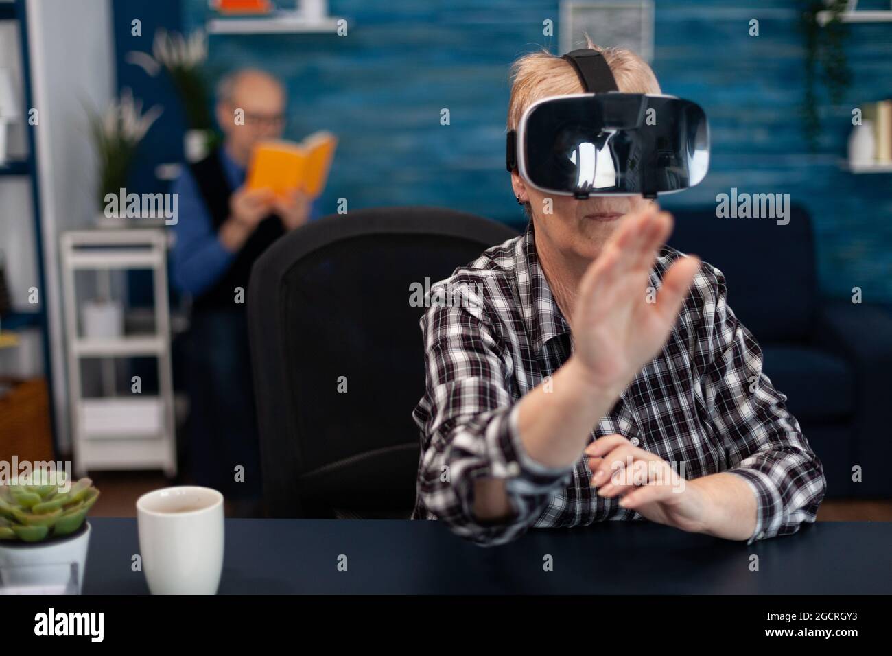 Happy senior woman wearing virtual reality headset doing hand gesture