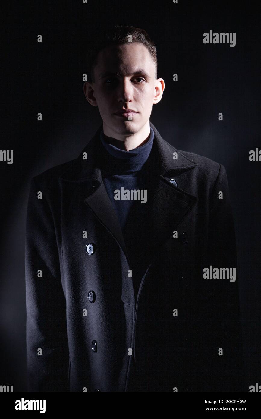 Stylish man in black coat in dark studio Stock Photo