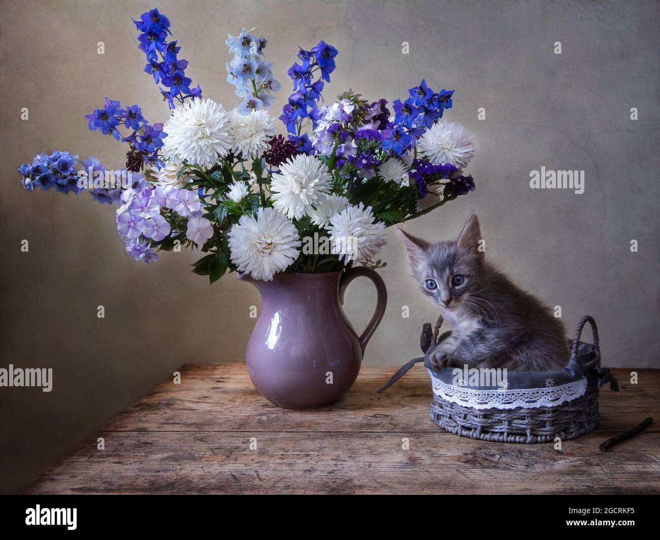 Still life with bouquet of flowers and little kitten in a basket Stock ...