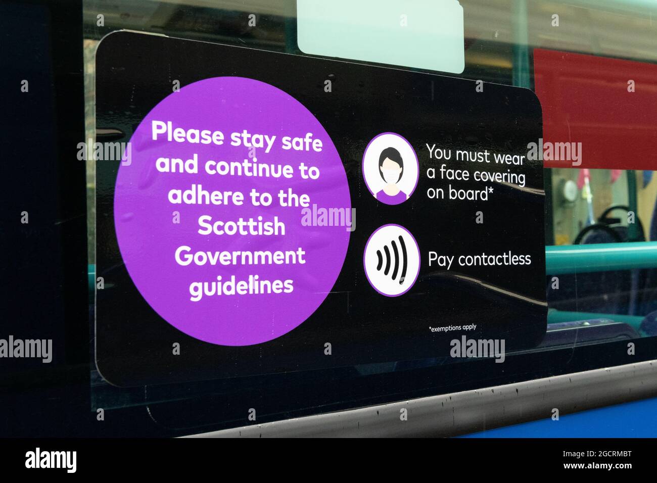Face mask face covering sign on First Bus bus window saying 'you must wear a face covering on board' and 'pay contactless' - Scotland, UK Stock Photo