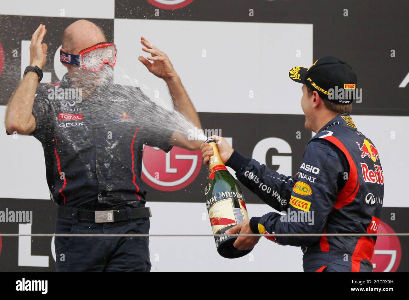 The podium (L to R): Adrian Newey (GBR) Red Bull Racing Chief Technical Officer wearing a mask with race winner Sebastian Vettel (GER) Red Bull Racing spraying the champagne. Korean Grand Prix, Sunday 14th October 2012. Yeongam, South Korea. Stock Photo
