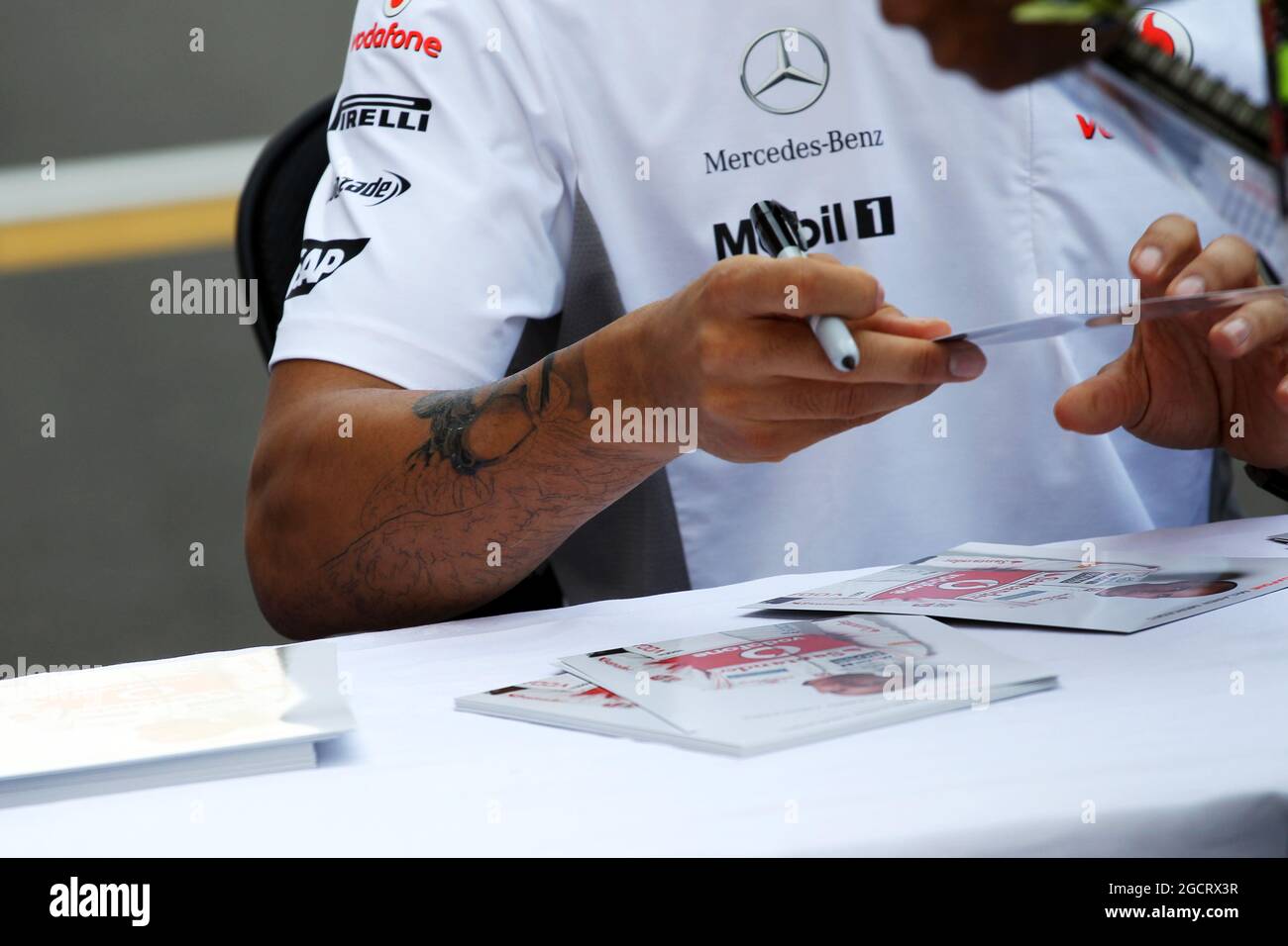 Lewis Hamilton (GBR) McLaren, with new tattoo, signs autographs for the fans. Indian Grand Prix, Thursday 25th October 2012. Greater Noida, New Delhi, India. Stock Photo