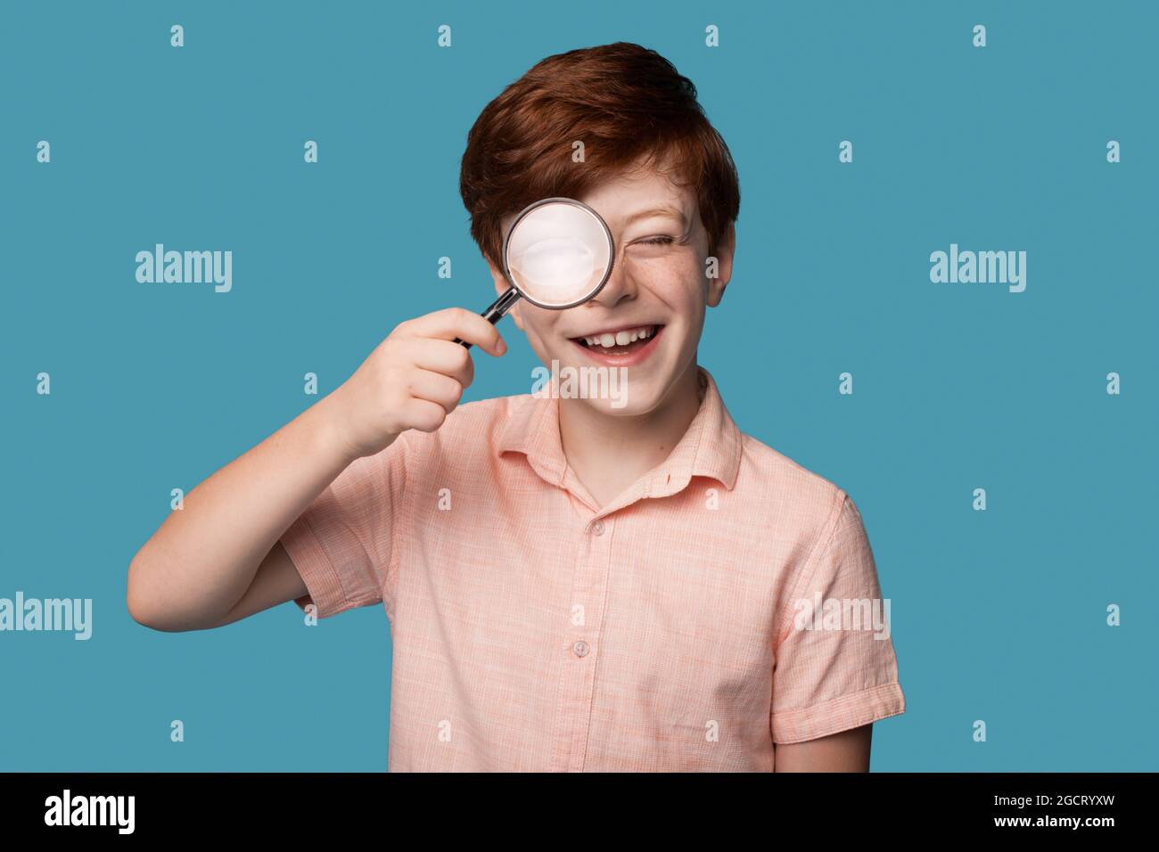 Boy With Ginger Hair Using Magnifier And Smile Educational Concept
