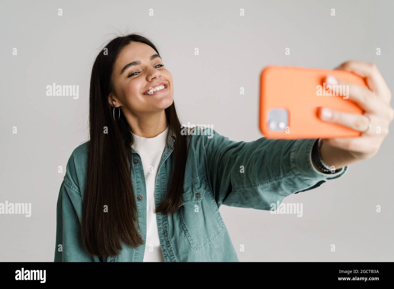Young smiling woman taking selfie photo on mobile phone isolated over ...