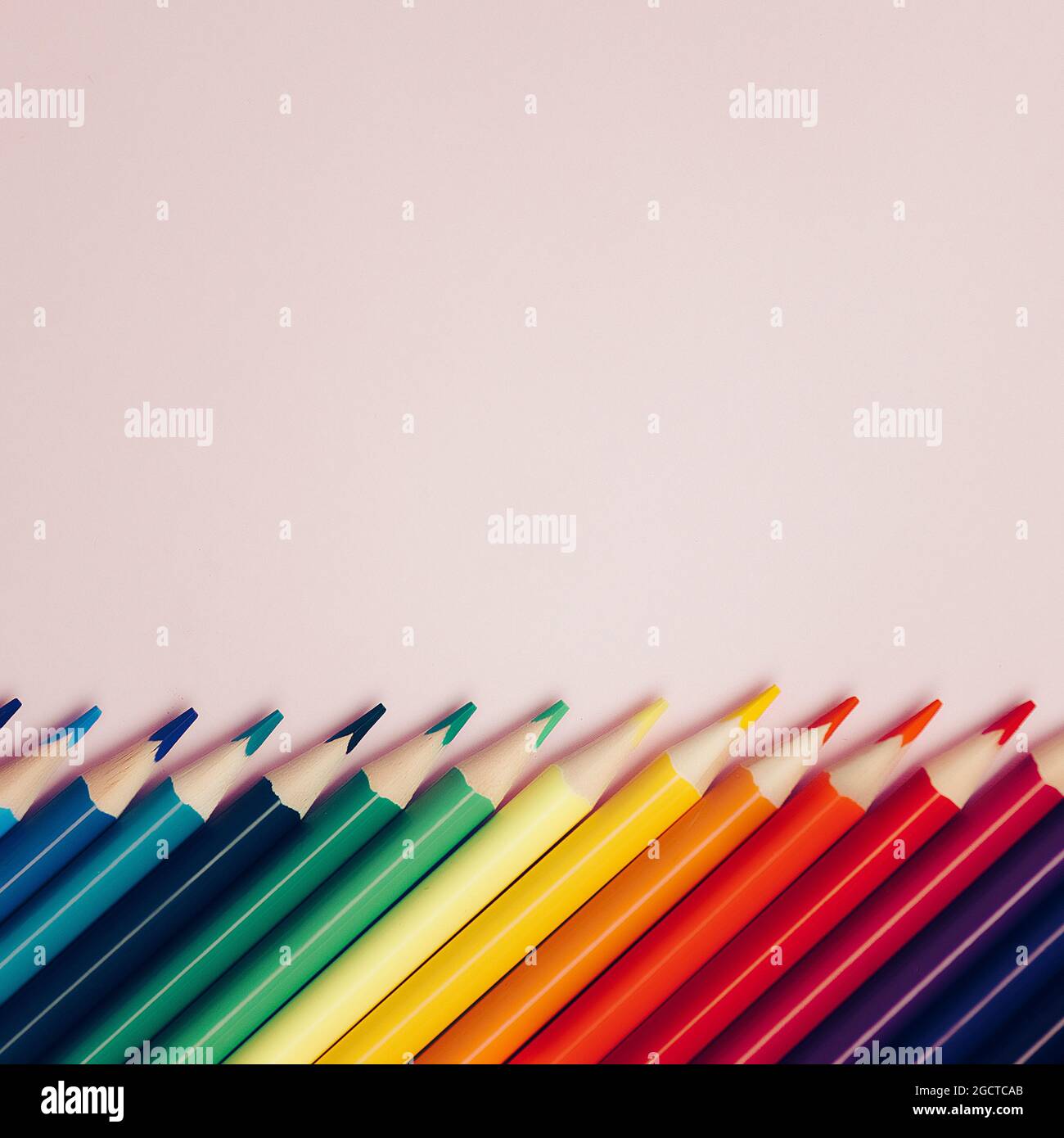 Colored pointed pencils lie on a pink background with space for copying ...