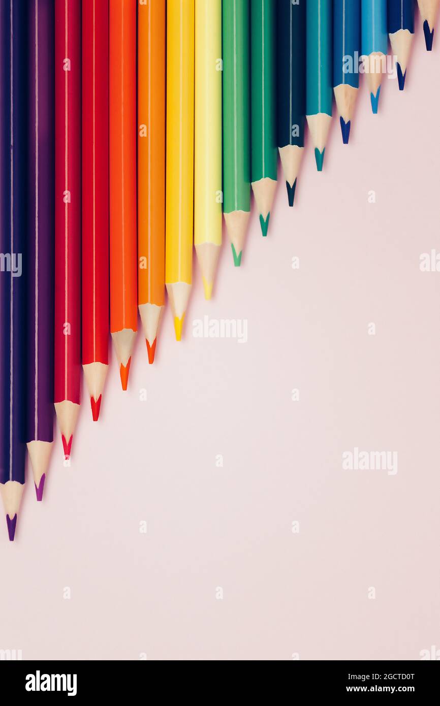 Colored pointed pencils lie on a pink background with space for copying ...