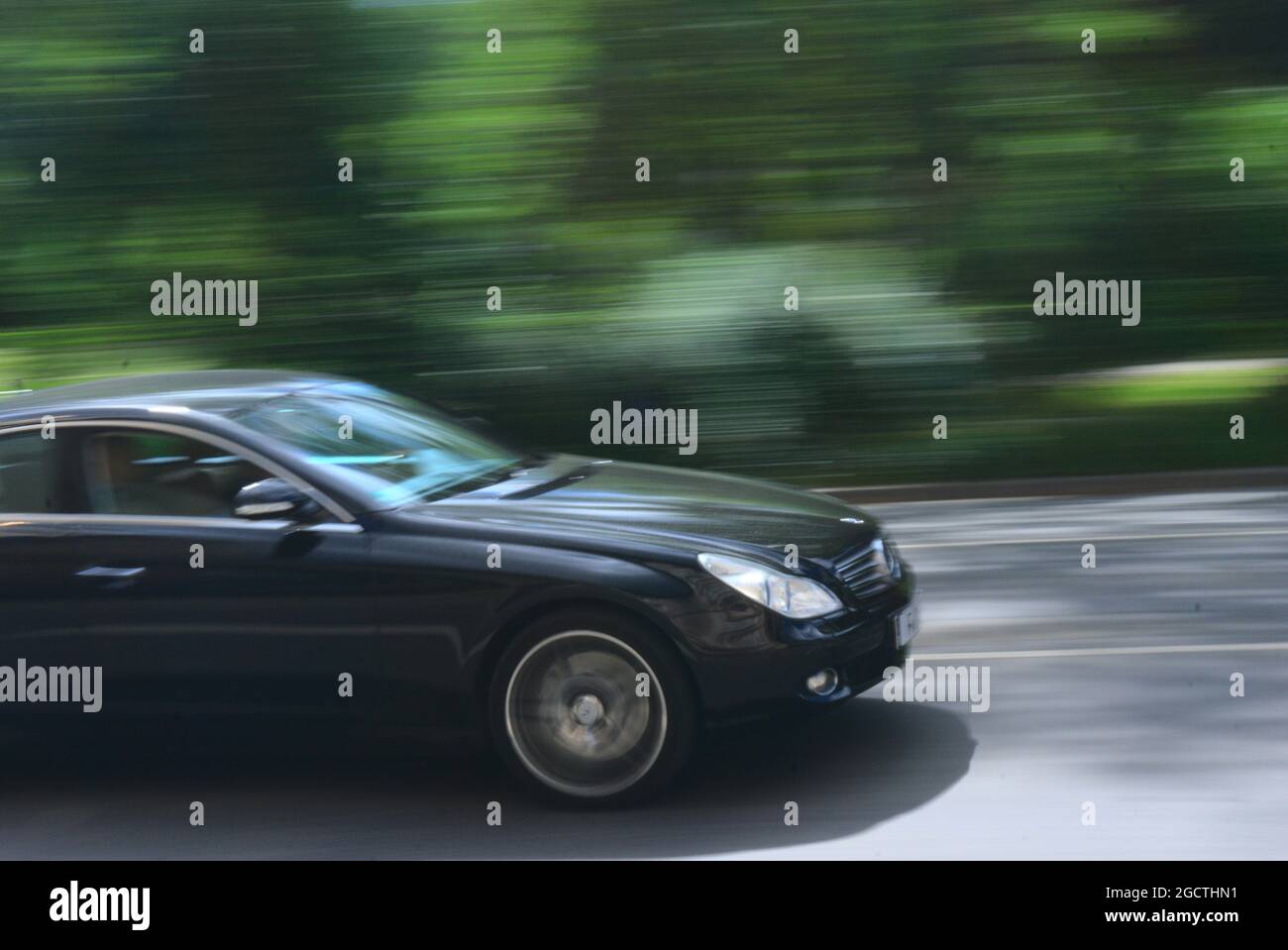 Black Mercedes limousine pacing through the city with a blurred park in the background in Frankfurt, Germany Stock Photo
