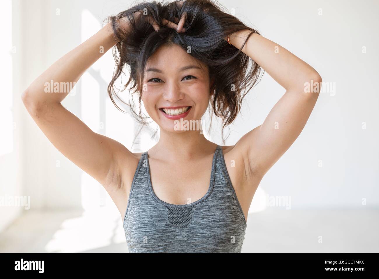 Young beautiful Asian girl smiles and plays with her hair. She is