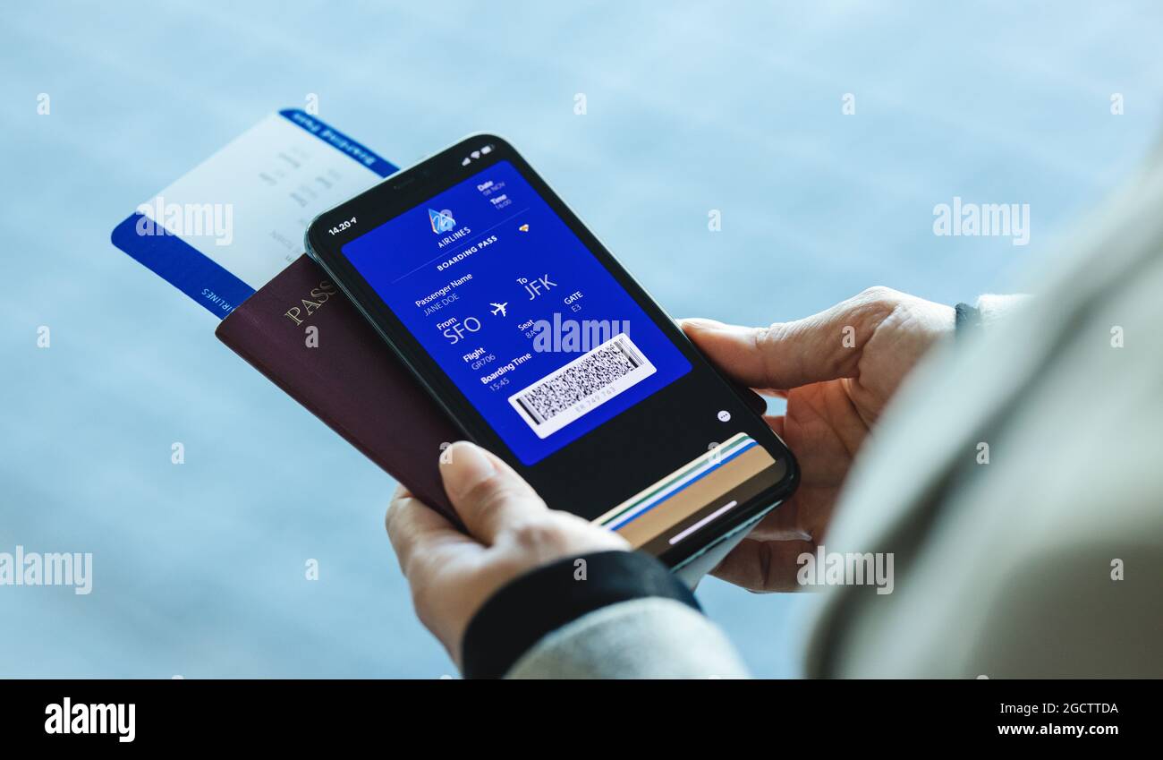 traveler holding mobile phone with electronic boarding pass on the screen. Passenger using digital boarding pass for air travel. Stock Photo