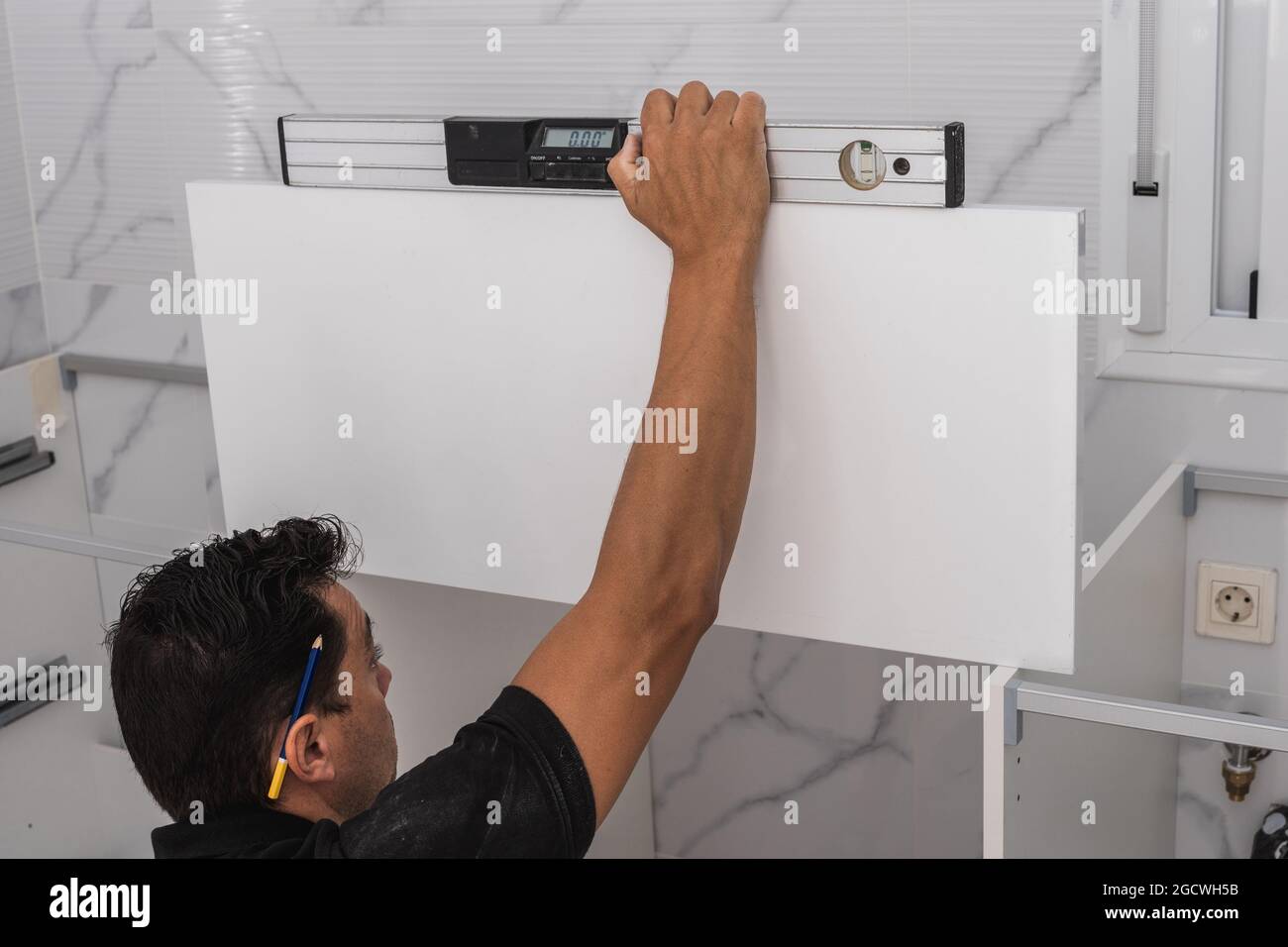 Man using a spirit level to install a kitchen unit Stock Photo
