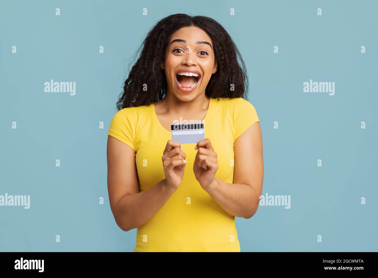 Trustful bank. Overjoyed african american woman demonstrating credit card and opening mouth in excitement Stock Photo