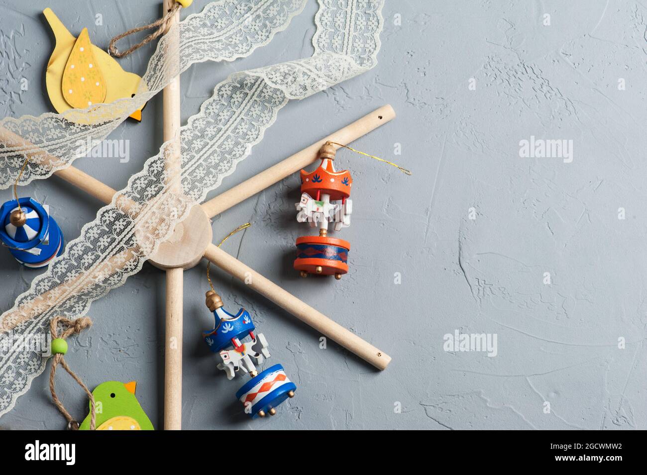 Flat lay of baby crib mobile with wooden colorful birds and carousels