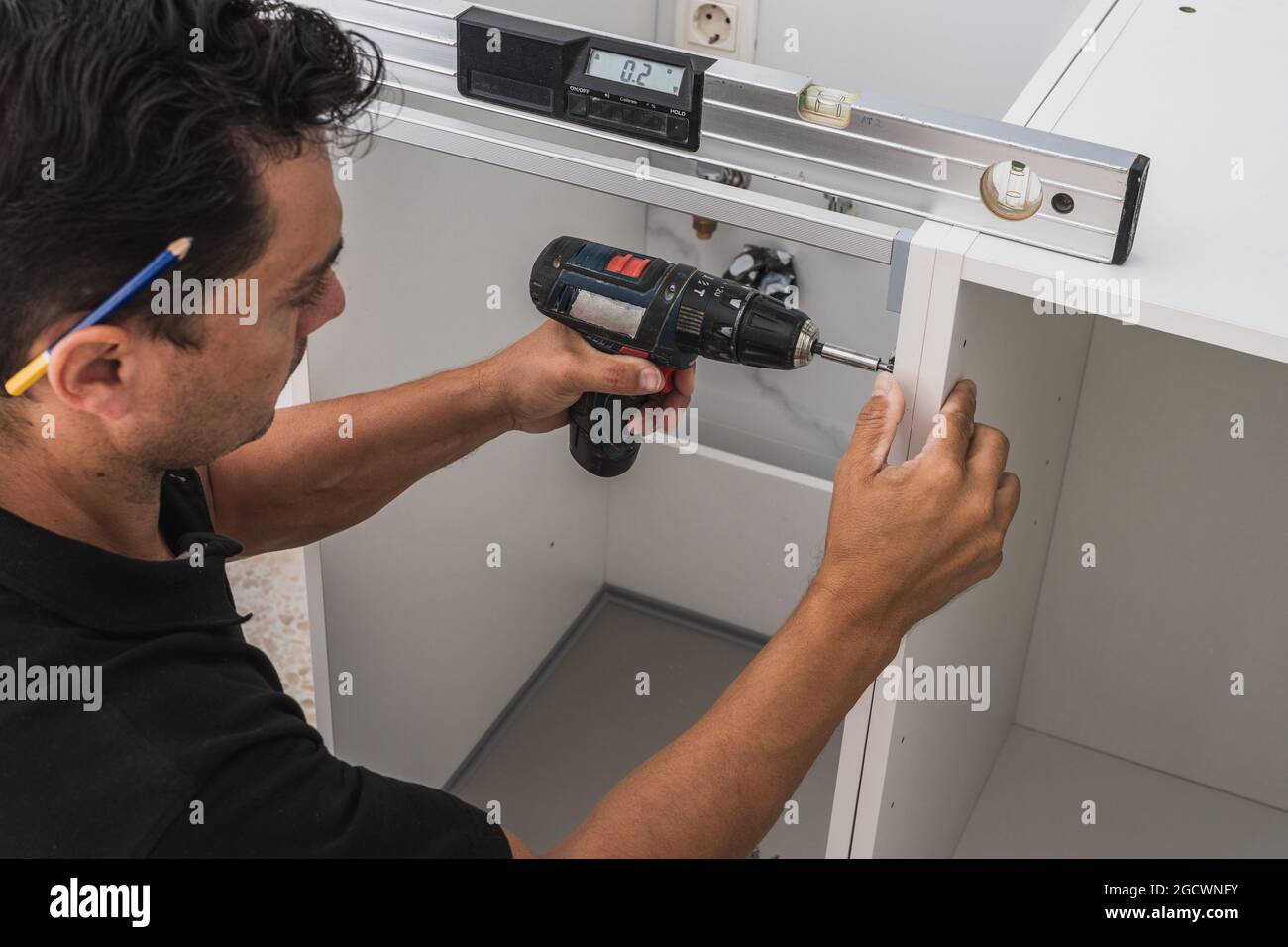 Kitchen installer using a drill to fix two pieces of a Stock
