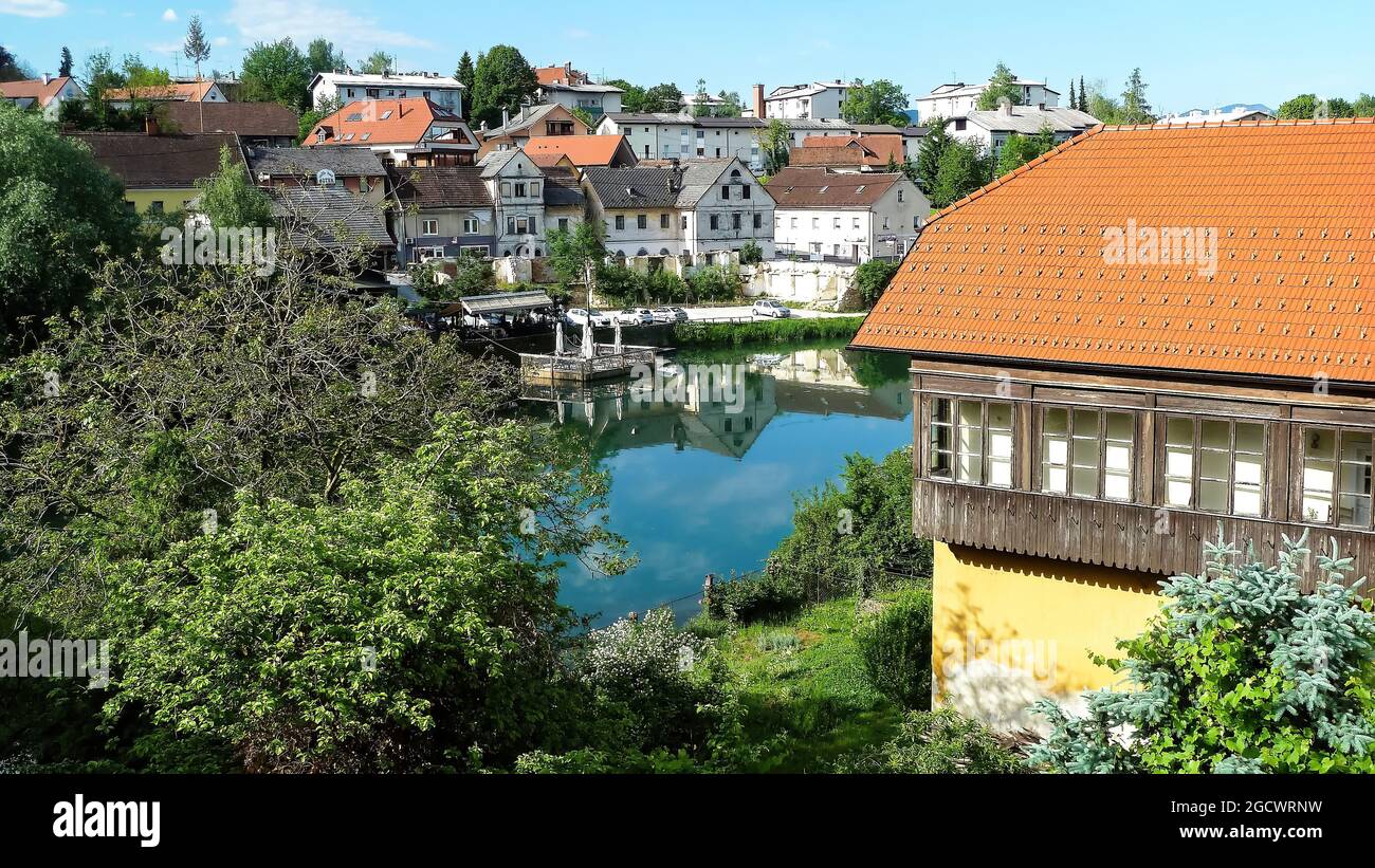 Novo Mesto, Slovenia - May 9. 2017: View over river Krka on village against summer sky Stock Photo