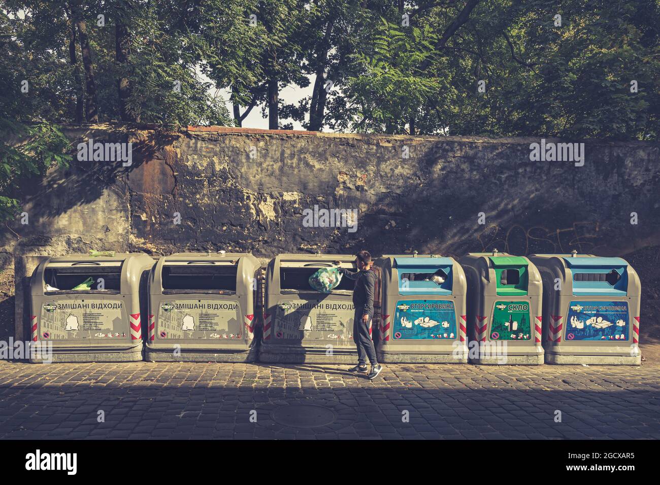 Row of trash cans for sorted garbage to recycling. Man throws litter