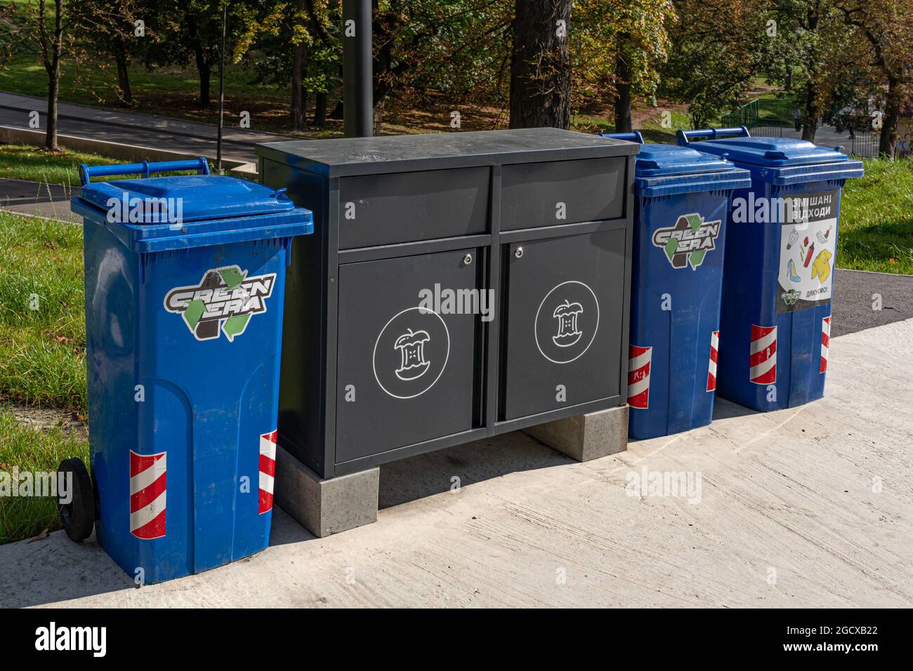 Pavement in park with trash recycling cans and lockers for sorted garbage. Sustainable lifestyle in urban environment. Environmental conservation. Lvi Stock Photo