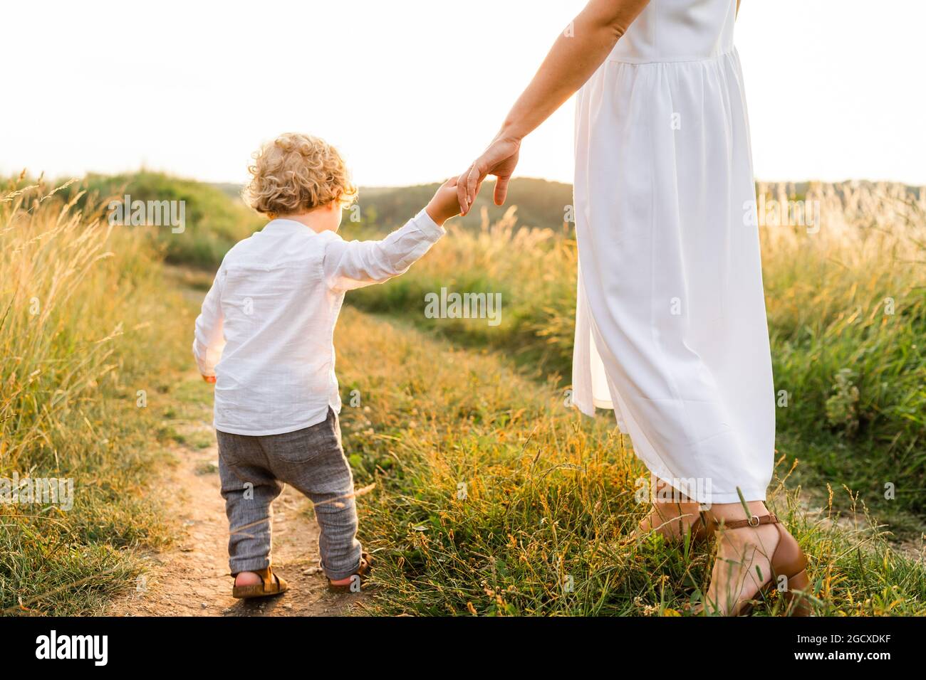 Little boy walking in nature holding his mother's hand Stock Photo