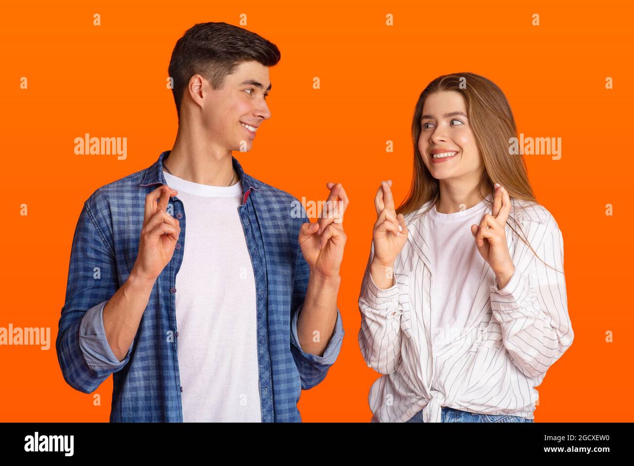 Luck and superstition. Cheerful millennial couple gesturing crossing fingers in hope Stock Photo