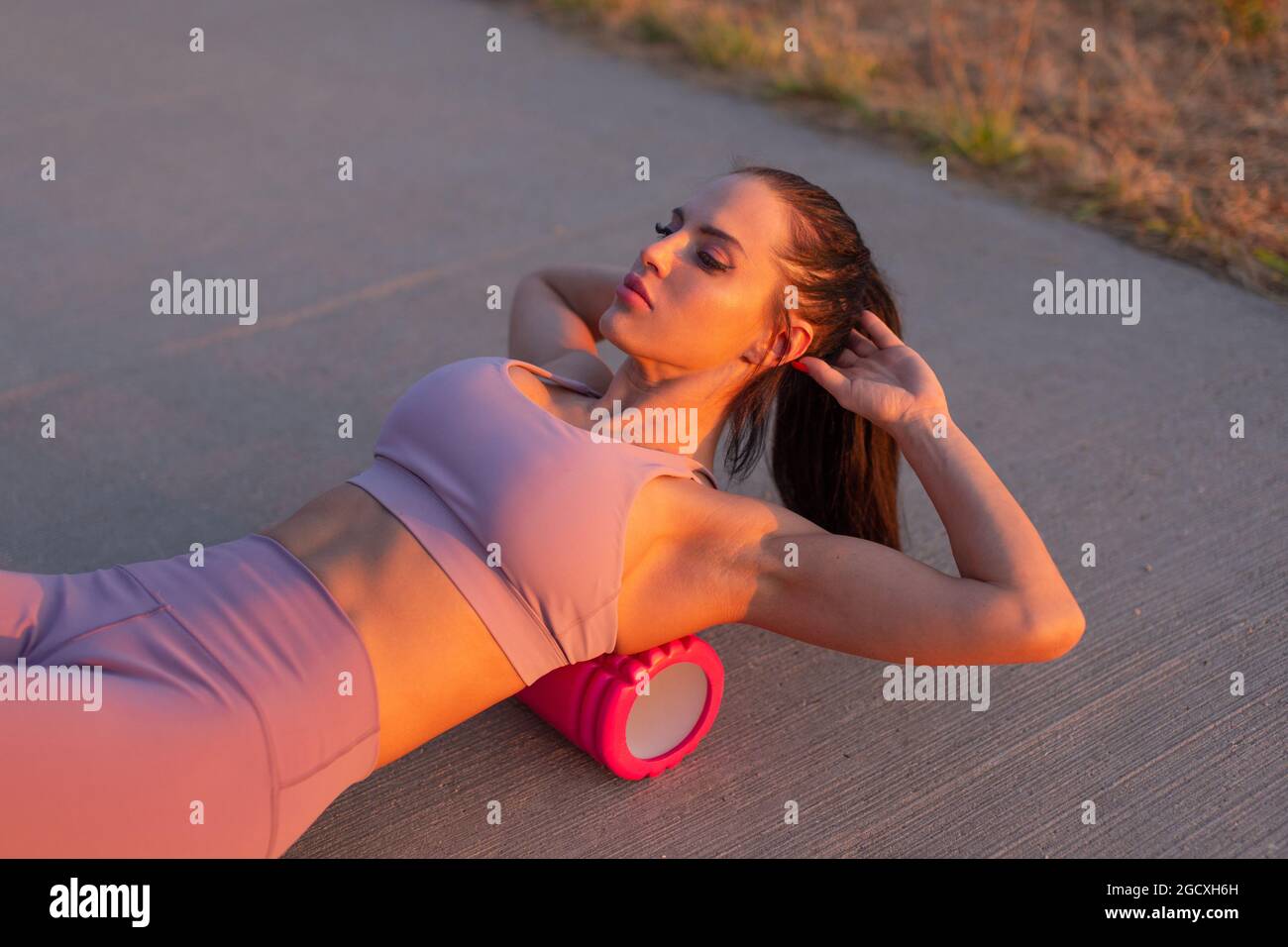 Young Caucasian woman doing exercise by foam roller at outdoors Stock Photo
