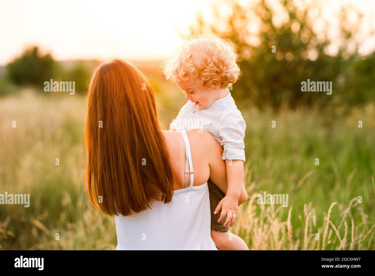 Mother holding son in her arms back view Stock Photo - Alamy