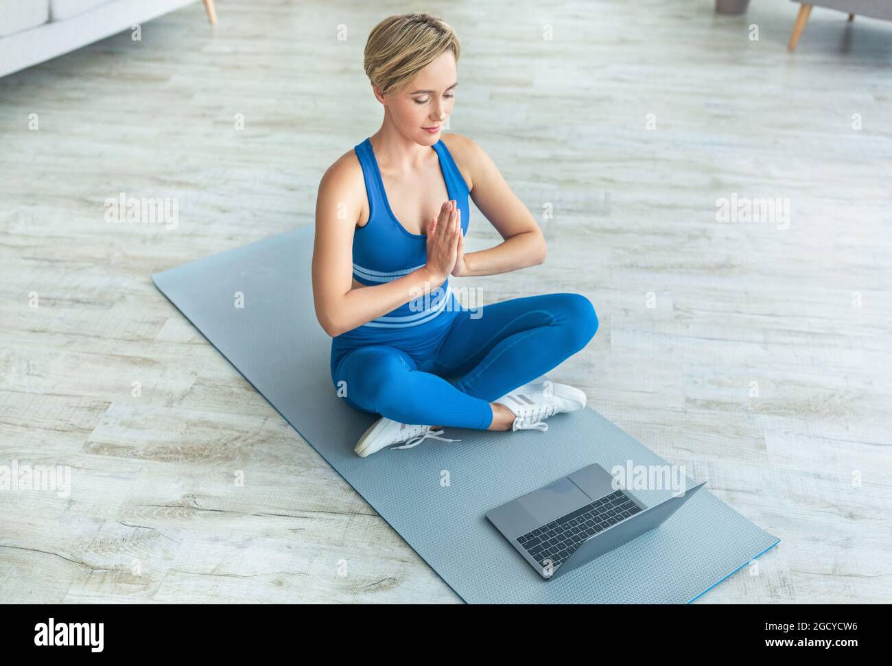 Woman meditating sitting in lotus position on mat with pc Stock Photo ...