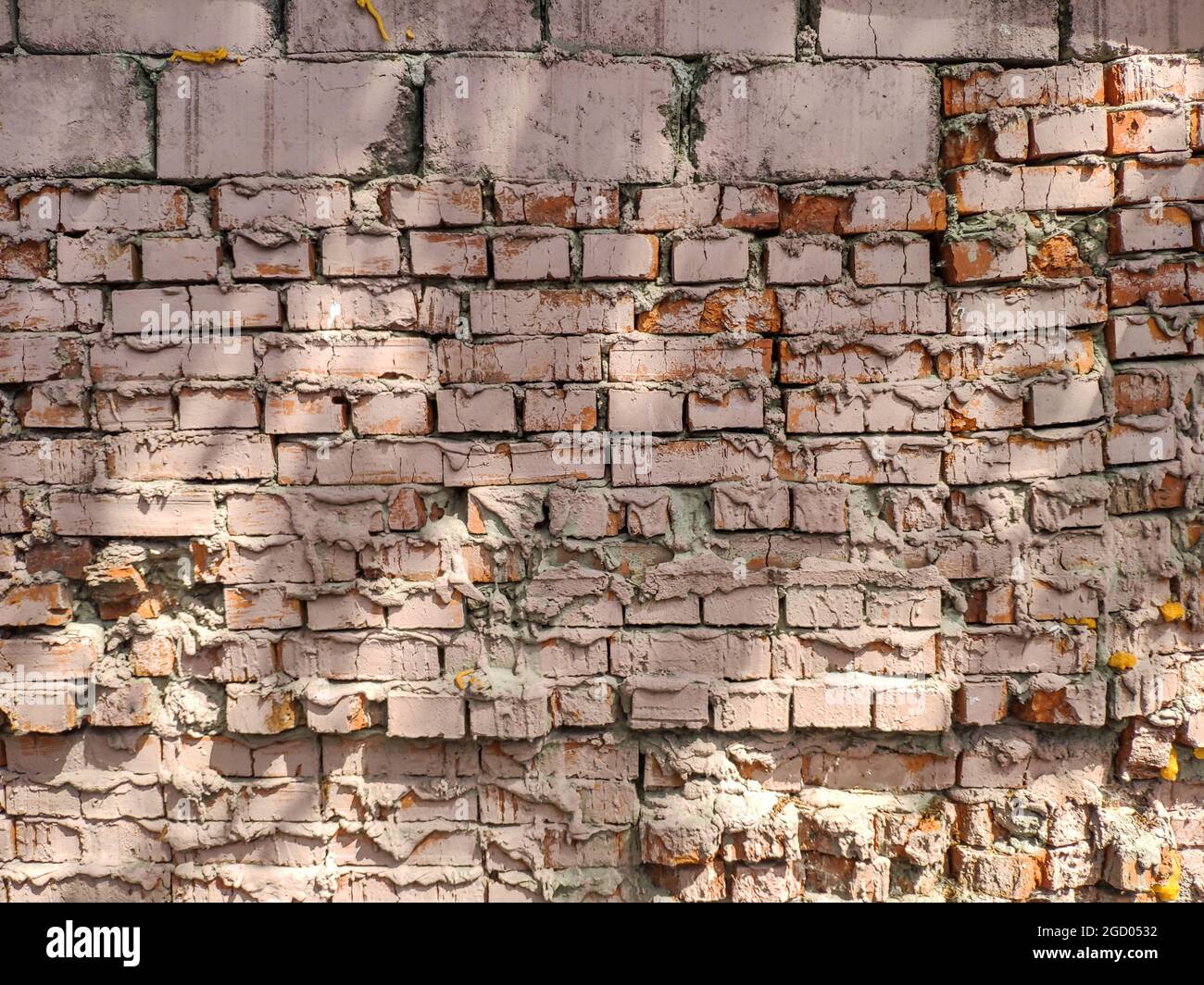 Old textured brick wall covered with pink paint. Stock Photo
