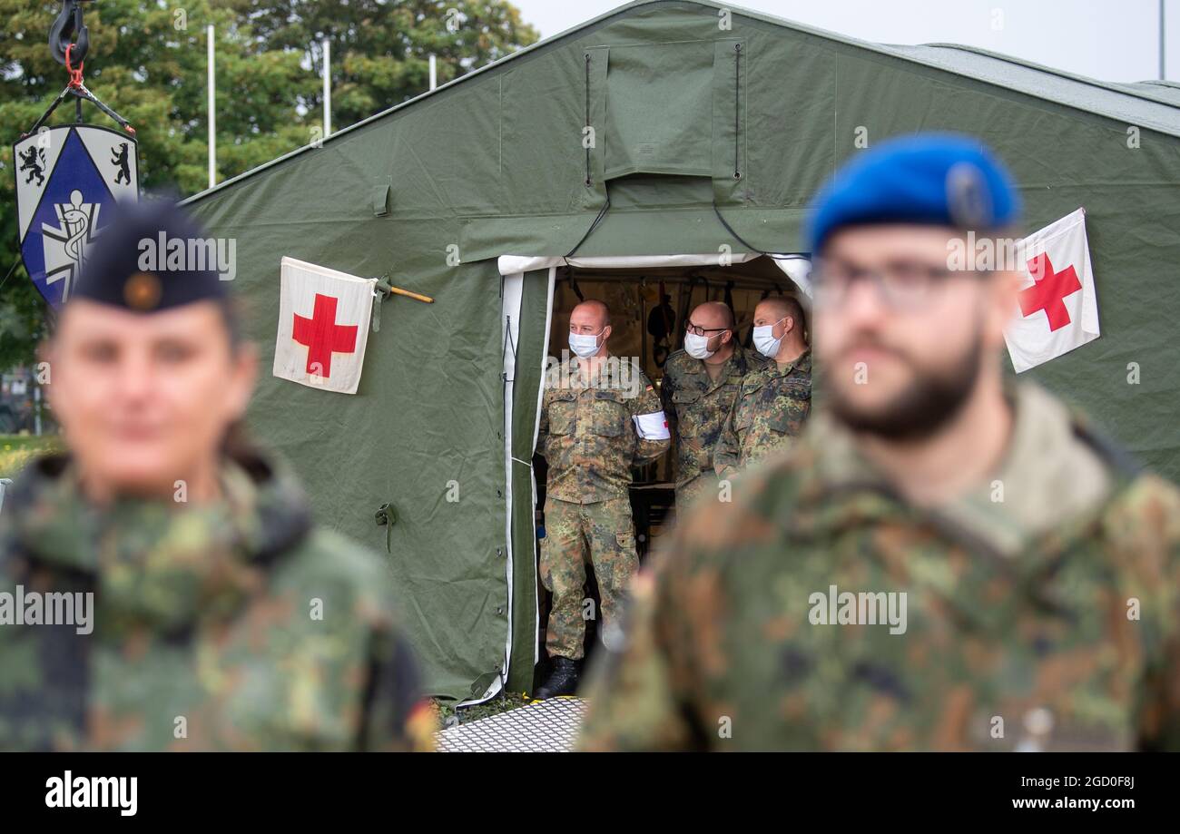 10 August 2021, Saxony-Anhalt, Weißenfels: Soldiers from the Bundeswehr  Medical Command in Weißenfels stand in front of a mobile rescue centre. As  part of her summer trip, Defence Minister Kramp-Karrenbauer visited the