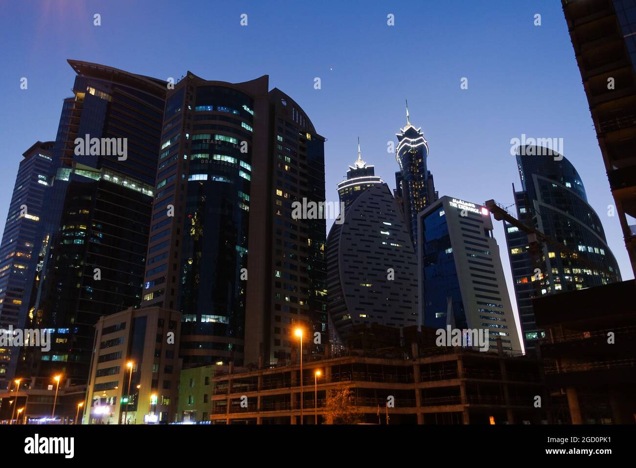 Night time photograph of The Exchange Building and other illuminated Towers in Dubai, UAE Stock Photo