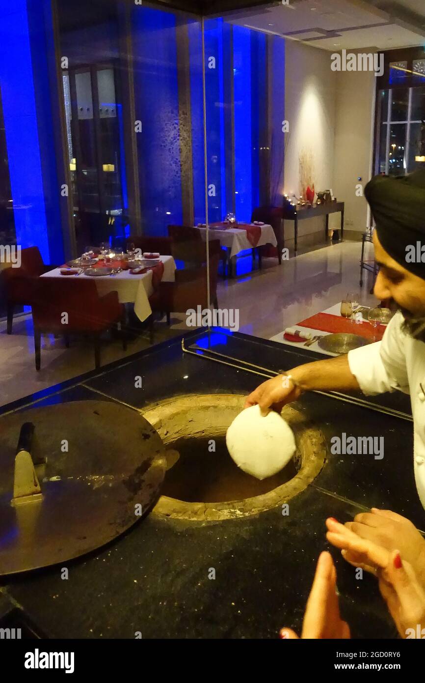 Cook invites customers to make a Naan Bread at the Ananta Indian Restaurant of The Oberoi Hotel in Dubai, UAE Stock Photo