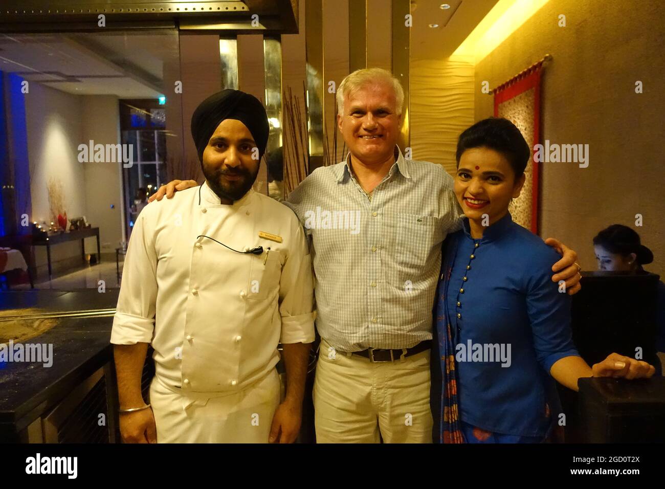 UK Actor Alan Carter poses with the Cook and Hostess at the Ananta Indian Restaurant of The Oberoi Hotel in Dubai, UAE Stock Photo