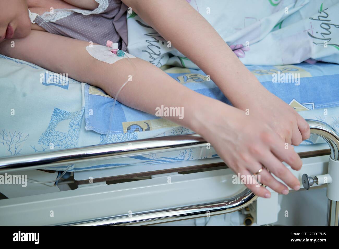 Hands with dropper needle and anesthesia injection. Pregnant woman with an IV on the bed Stock Photo