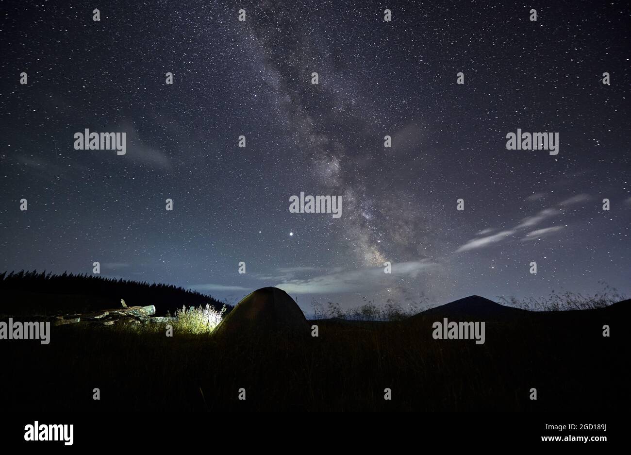 Amazing starry night sky in the mountains and tent at campsite. Millions of stars over single tent in the middle of mountain meadow. Concept of closen Stock Photo