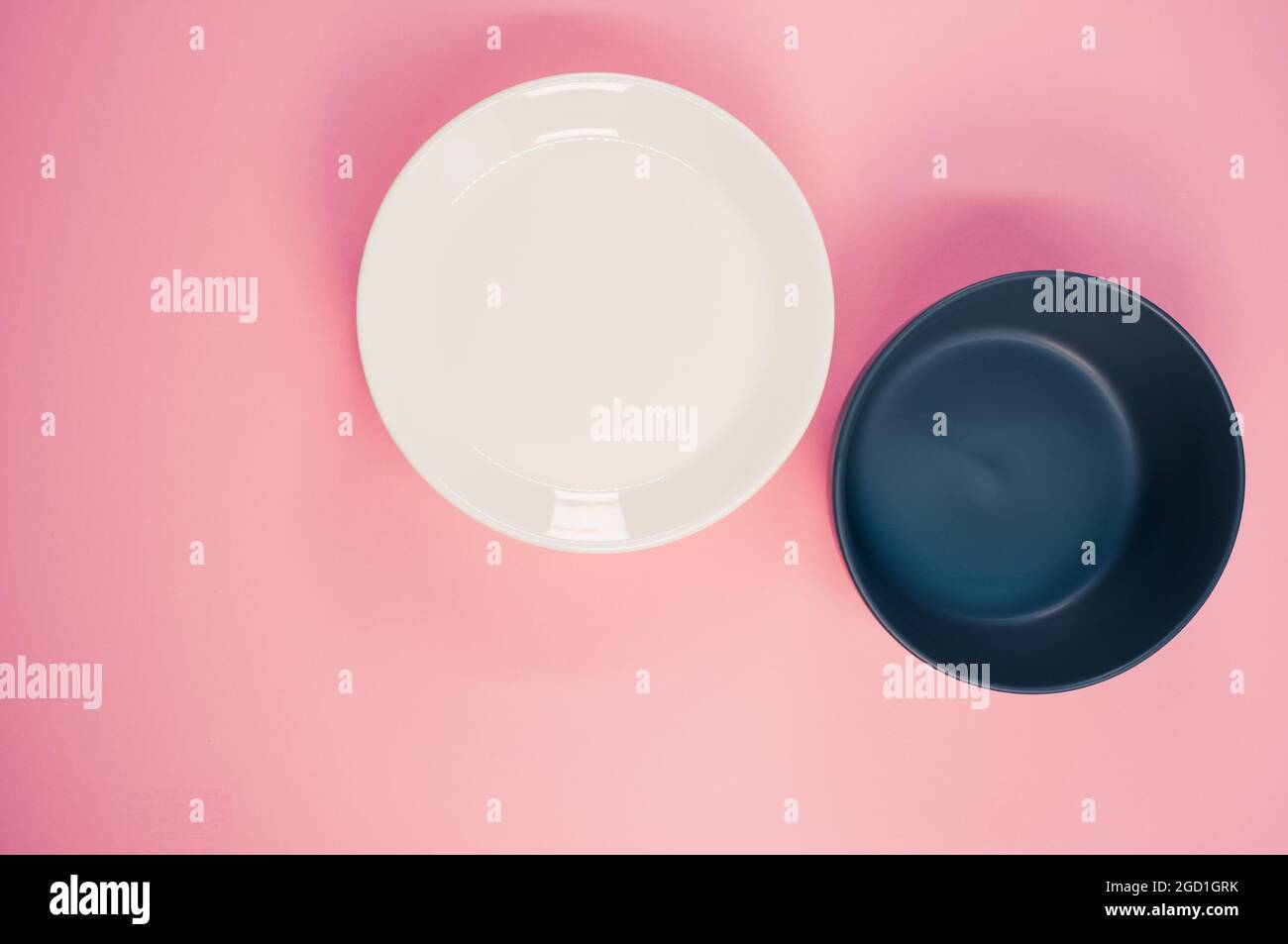 Top view of empty ceramic black and white plates on a pink background ...