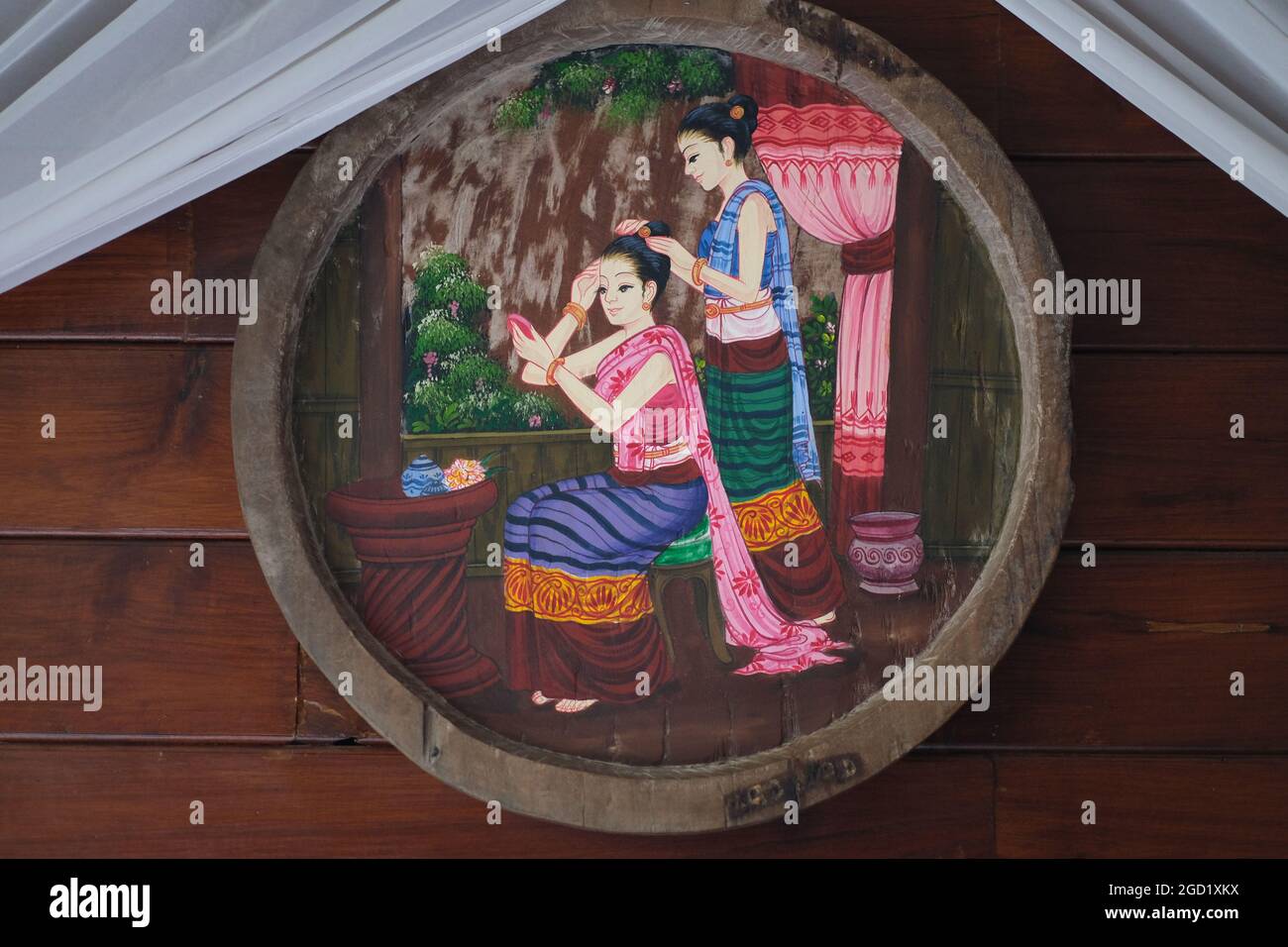 A decorative folk-art painting, depicting scene of Siam's olden times, is hanging on a wooden wall Stock Photo
