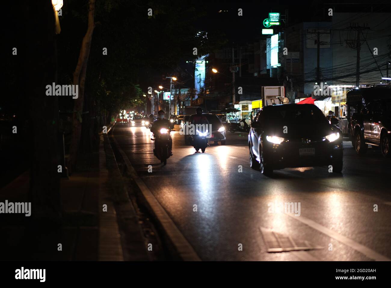 A road in big city at late evening: heavy traffic under a big trees in Chiang Mai, Thailand Stock Photo