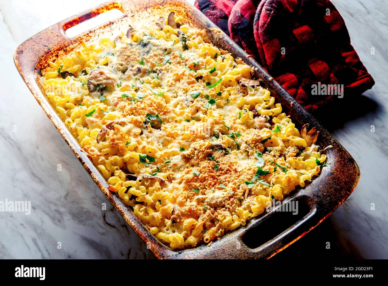 Mushroom spinach mac and cheese casserole with oven mits Stock Photo
