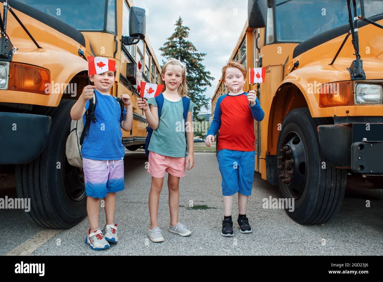 Proud happy children students boys and girl holding waving Canadian flags. Education and back to school in September. Group of friends kids near yello Stock Photo