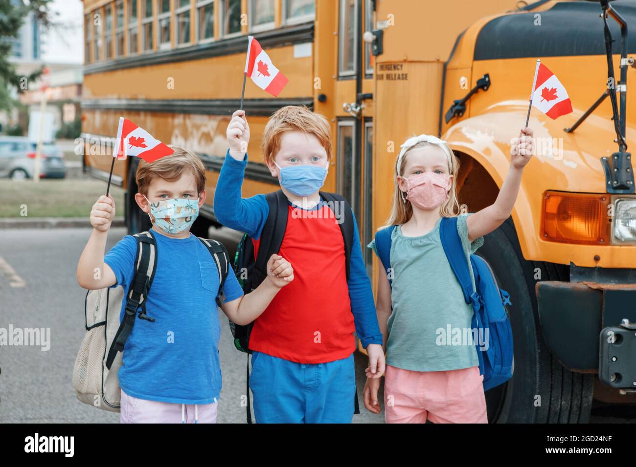 Proud happy students children with face masks holding Canadian flags. Education and back to school of kids classmates in September. New normal Stock Photo
