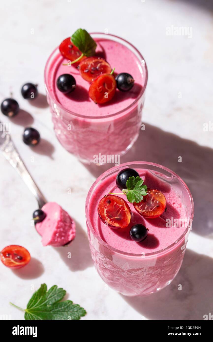 Berry mousse garnished with currants and gooseberries on a marble background. Stock Photo