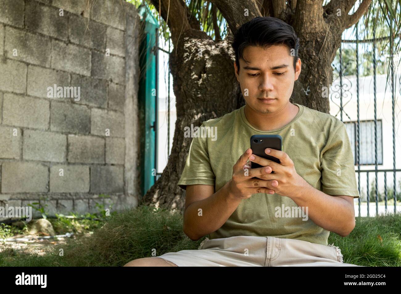 Young man using his smart phone sitting on the grass Stock Photo