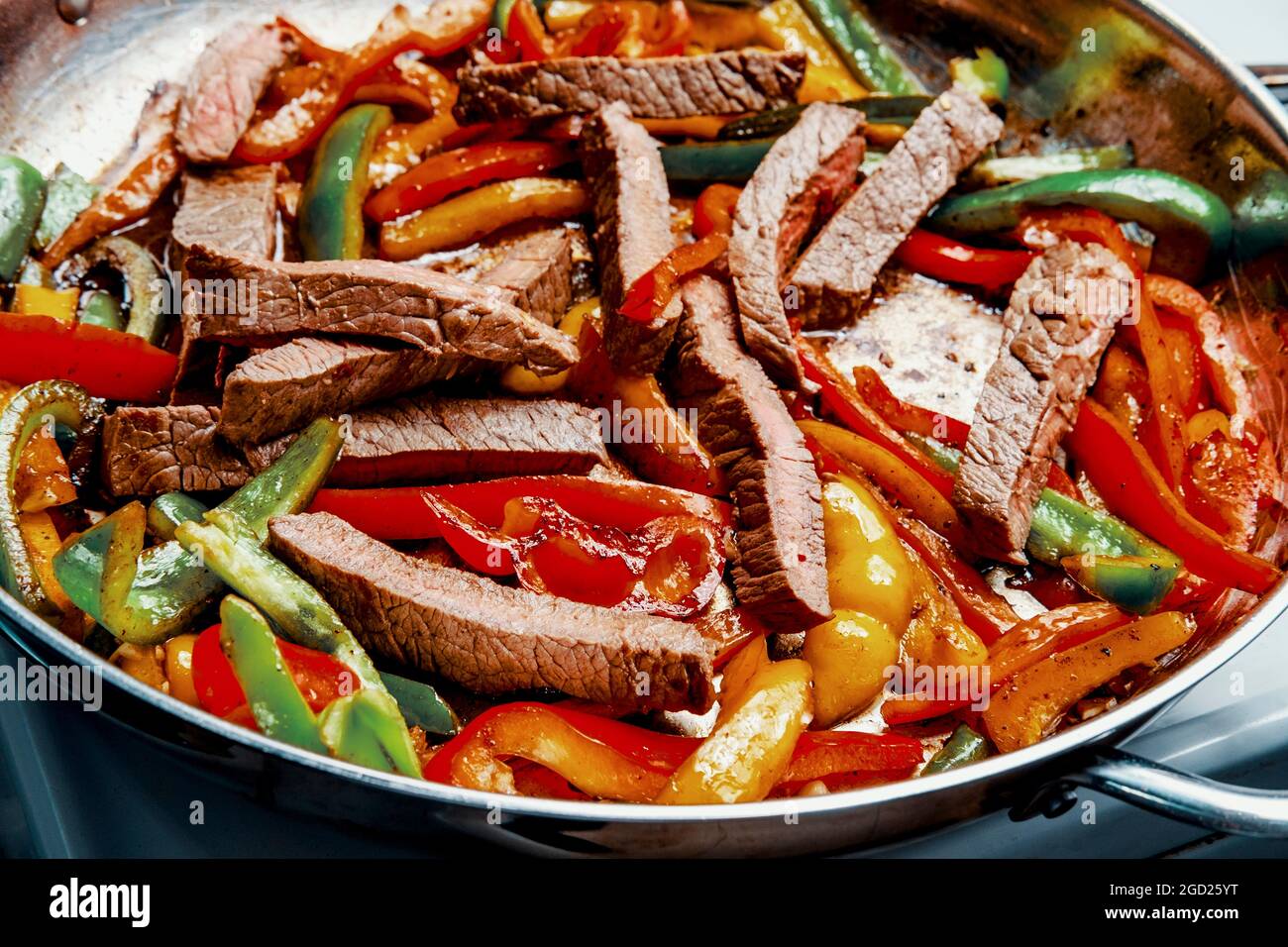 Cooking Mexican top round steak fajitas in giant pan on stovetop Stock