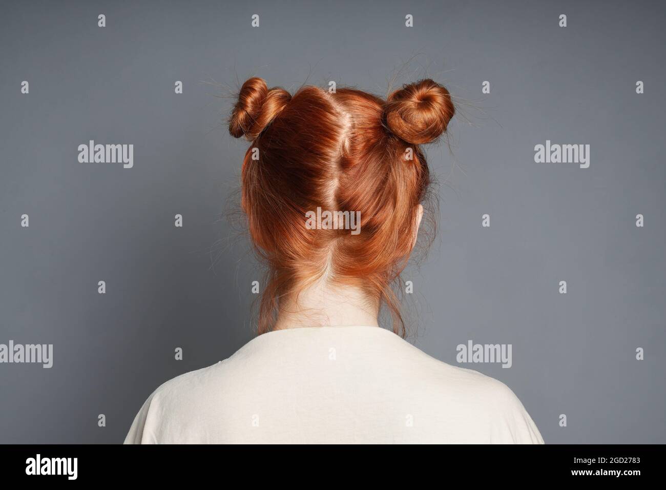 back view of red-haired woman with space buns hairstyle Stock Photo