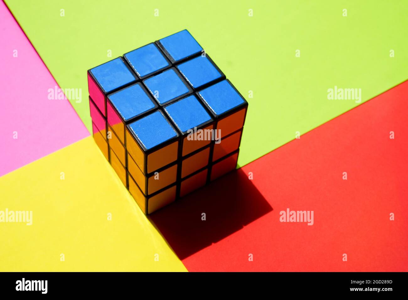 Rubik's cube by blue side on a sunny colorful table. Stock Photo