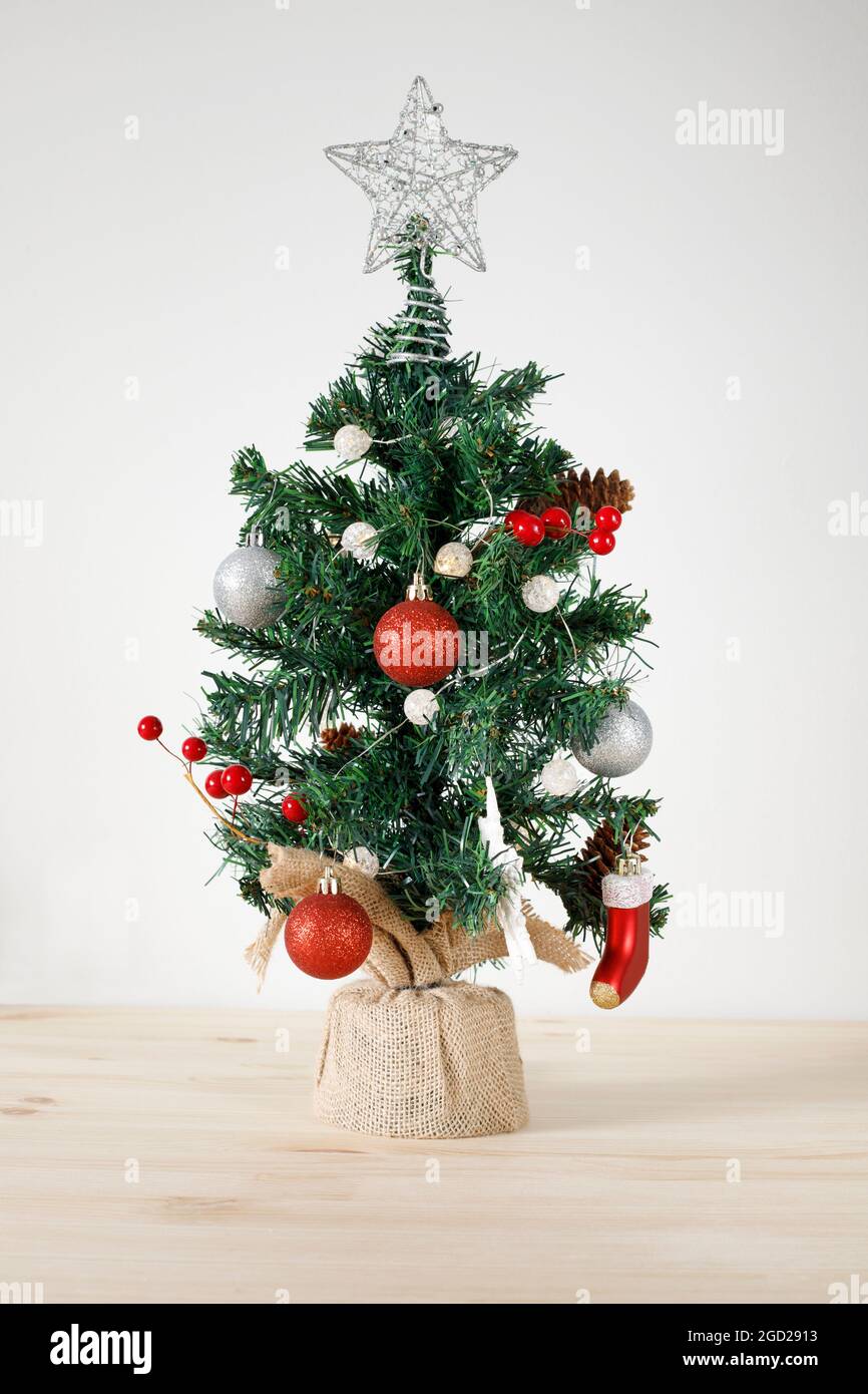 Christmas tree with ornaments on wooden table and white wall background