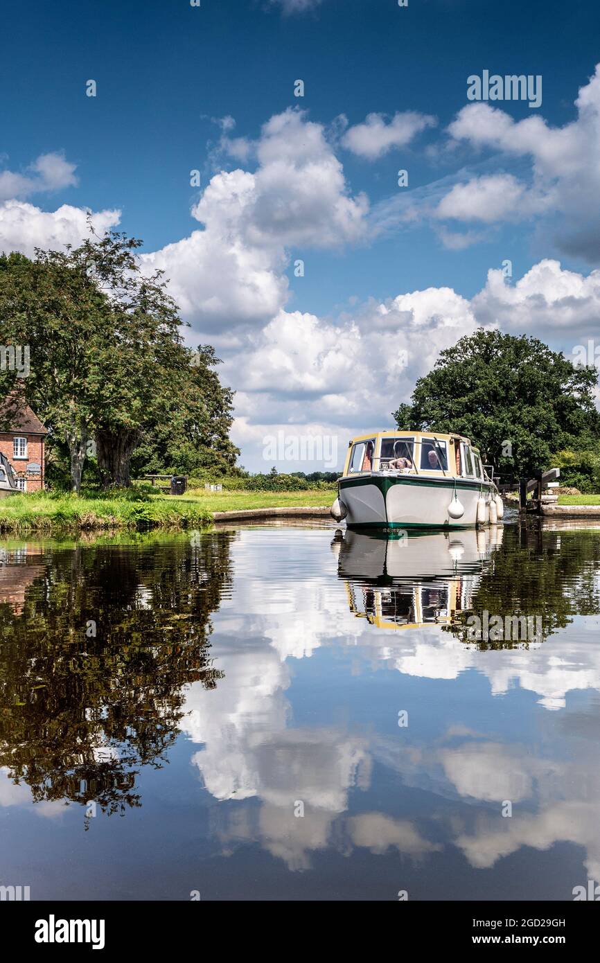 Staycation motor boating River Wey summer, cabin cruiser exiting Papercourt Lock navigating upstream Papercourt Lock River Wey Navigations Surrey UK Stock Photo