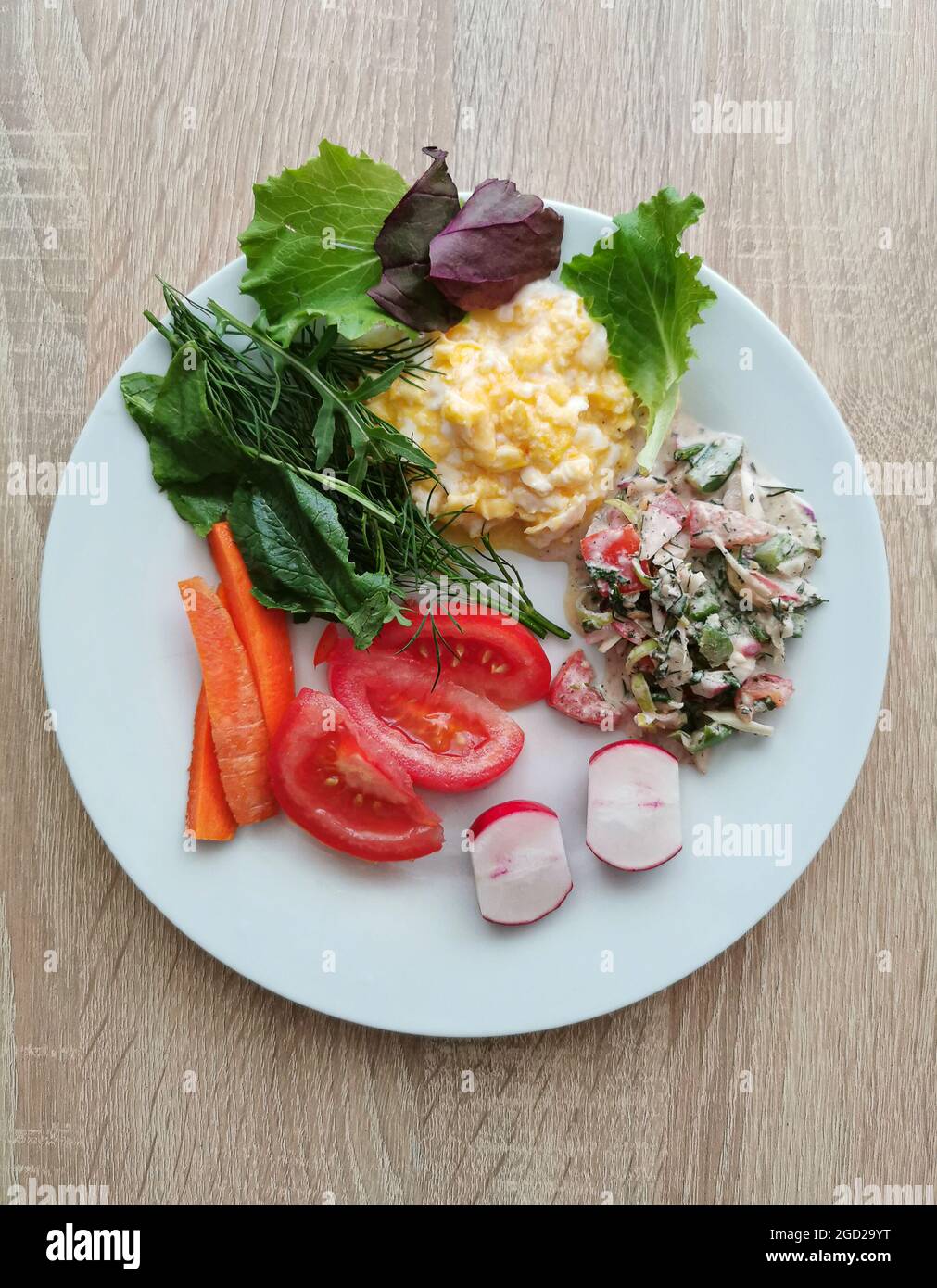 A healthy and balanced breakfast. Scrambled eggs, tomato, carrot, radish, salad, green leaves of fresh vegetables Stock Photo