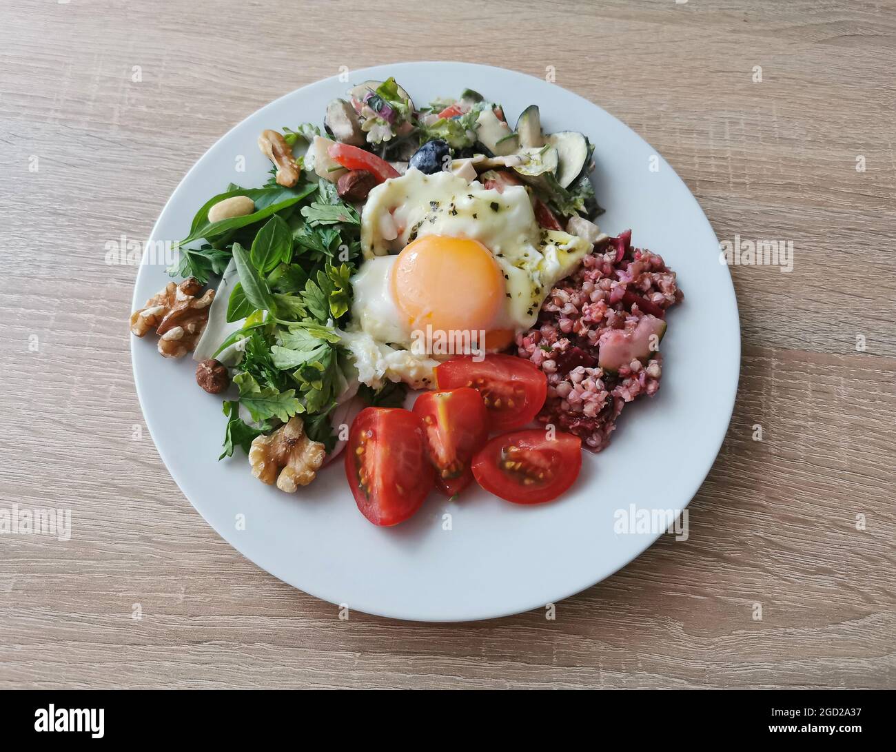 A healthy and tasty summer breakfast. Soft boiled egg, buckwheat groats, colorful vegetables and nuts Stock Photo